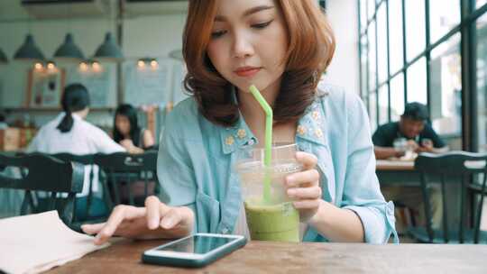 咖啡厅内边喝咖啡边使用手机的青年女人