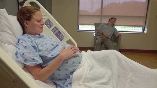 孕妇在病床上试图叫醒丈夫