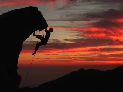 日落时分男人爬上崎岖的山峰视频素材模板下载