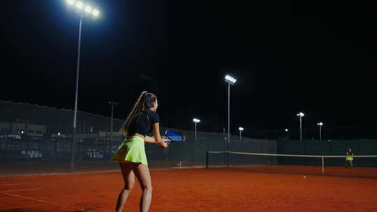 美丽的年轻女网球运动员在户外球场进行夜间