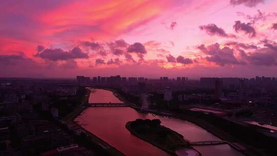 城市上空紫红色朝霞下的河流与建筑