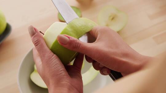 双手在木板上剥绿苹果