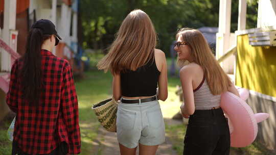 慢动作后视三个戴墨镜的女孩在阳光明媚的夏