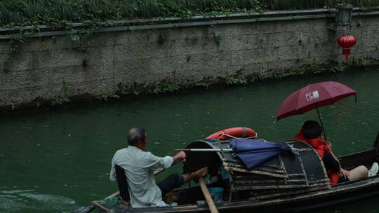 绍兴小雨中中船夫划着乌篷船载客前行