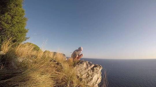 男人坐在海边岩石上看海景