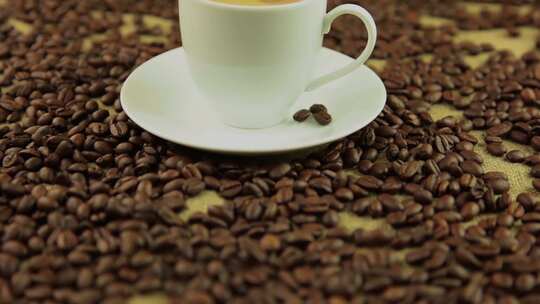 摇摄铺满咖啡豆的桌面上一杯冒着热气的咖啡