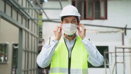 由于Covid19大流行，亚洲工人在建筑现场摘下防护面罩。