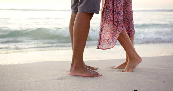 日落时分，赤脚混血夫妇站在沙滩上