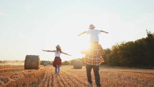 一家人一起走在麦田里的后景，用稻草做的草垛
