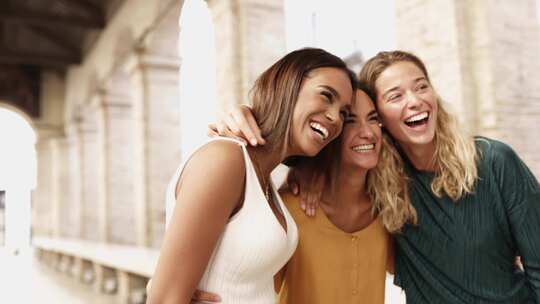 三个快乐的多种族女人一起笑，在街上玩得开心