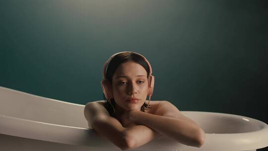 头戴耳机的女人坐在浴缸里