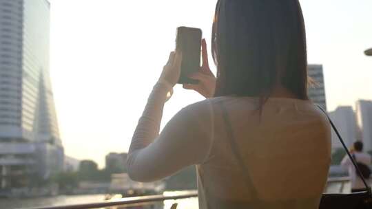 女孩用手机拍摄城市景观