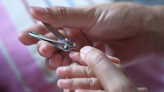 妈妈用剪刀给宝宝剪指甲。