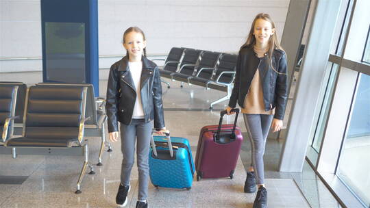 机场拉着行李箱的两个小女孩
