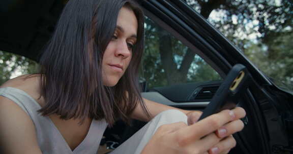 迷人的黑发女人在汽车公路旅行聊天使用手机