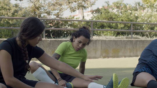女足球运动员坐在球场上做拉伸视频素材模板下载