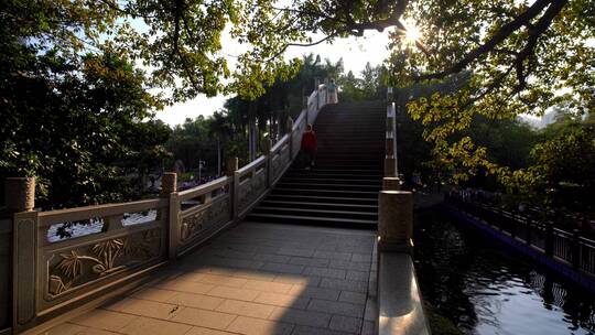 夕阳照耀拱桥戴口罩的游人下台阶