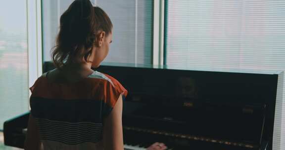 靠近窗户弹钢琴的女人
