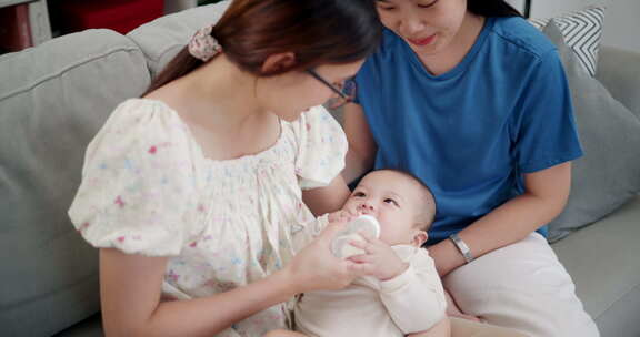 两个年轻的亚洲女人在家里开心地和一个婴儿