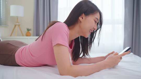 亚洲有魅力的女人早上在家床上用手机聊天。