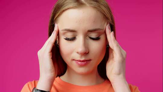 粉红色背景下经历头痛的年轻女子视频素材模板下载