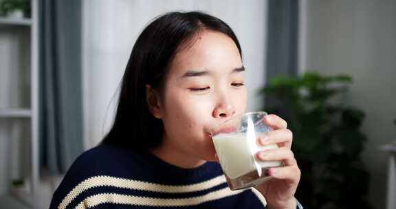 年轻的亚洲女人喜欢在家里的餐桌上吃早餐。