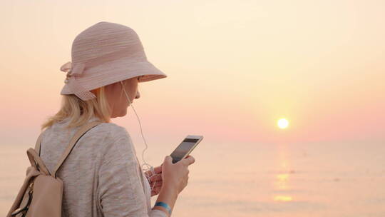 日出下的女游客在玩手机