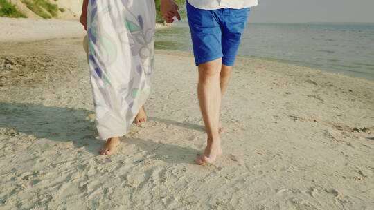 一对年轻夫妇赤脚走在沙滩上