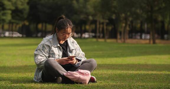 女大学生在草上上看手机浏览社交媒体