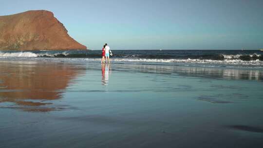 走在海滩的一对夫妇在日落时分视频素材模板下载