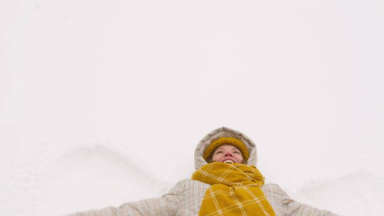 躺在雪上移动手臂的女人的俯视图