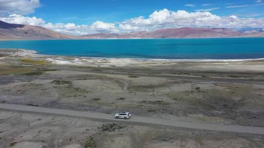 航拍越野车行驶在佩枯措湖边的土路上