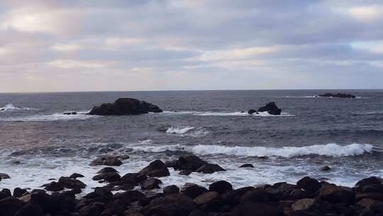 夏季一望无际的海平面海浪撞击在灰色岩石上