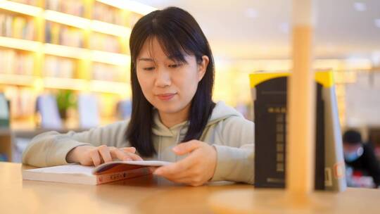 年轻女子图书馆在书架前翻看书本学习