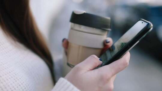 女生捧着咖啡杯玩手机视频素材模板下载
