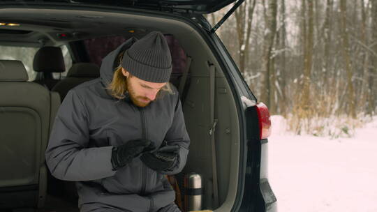 冬季坐在汽车后备箱的男人视频素材模板下载