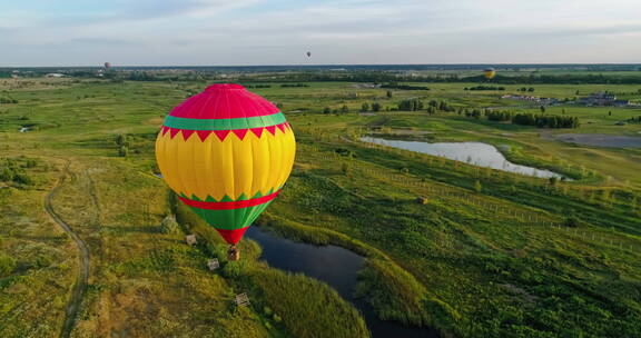 航拍飘在湖泊地上空的热气球