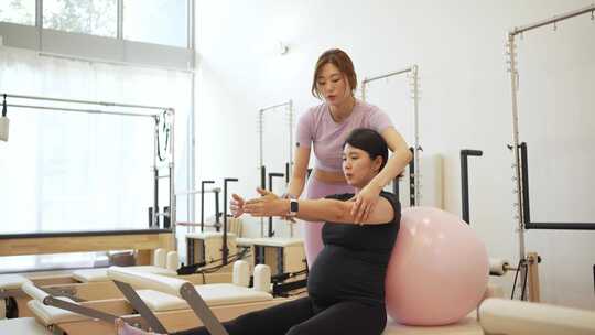 女人健身房练习瑜伽指导孕妇瑜伽康复练习视频素材模板下载