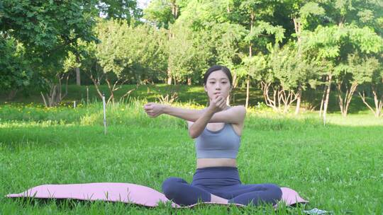 户外草地上做瑜伽的年轻女性身穿运动服装