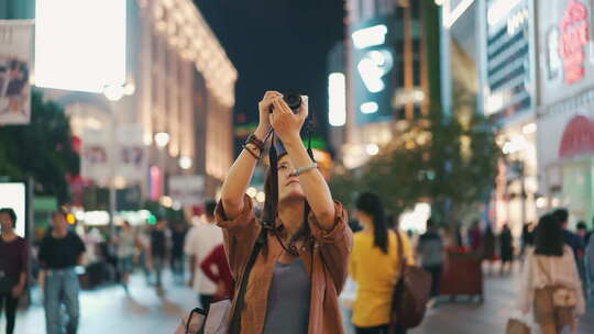 步行街拿相机拍照的女性游客