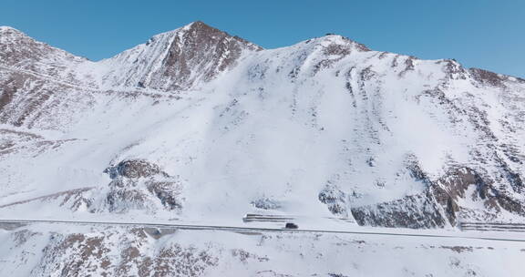 小汽车行驶在冬季白雪覆盖夹金山脚下公路上