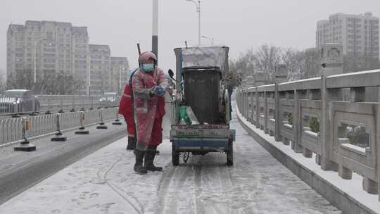 环卫工人冒着大雪在街上撒盐防止路面结冰