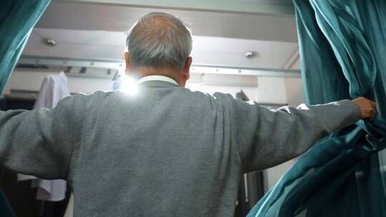 中老年男士拉开窗帘微笑看向窗外