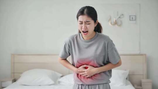 女孩卧室中捂着肚子显痛苦