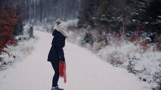 女人在雪地里跳跃着甩起围巾