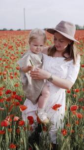 妇女抱着孩子走在罂粟花地上
