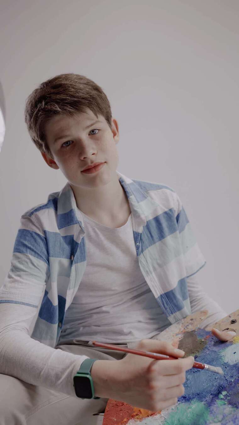 一个英俊的男孩拿着调色板摆姿势