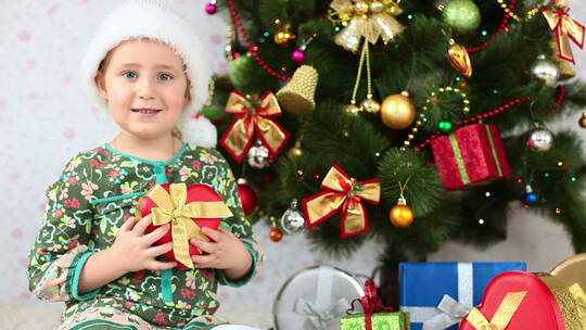 女孩坐在圣诞树旁边送礼物