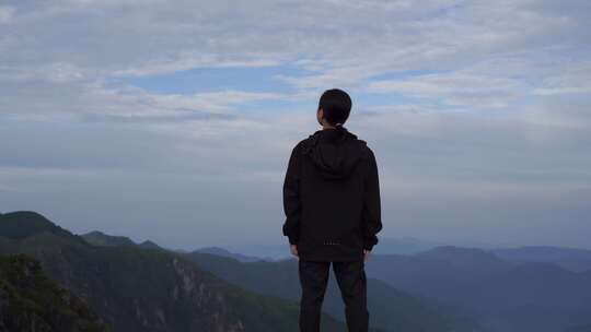 女性青年站在山顶看风景背影看远山感受自然