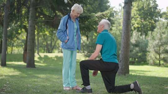 感恩的老年妻子拥抱丈夫在春夏公园的运动鞋